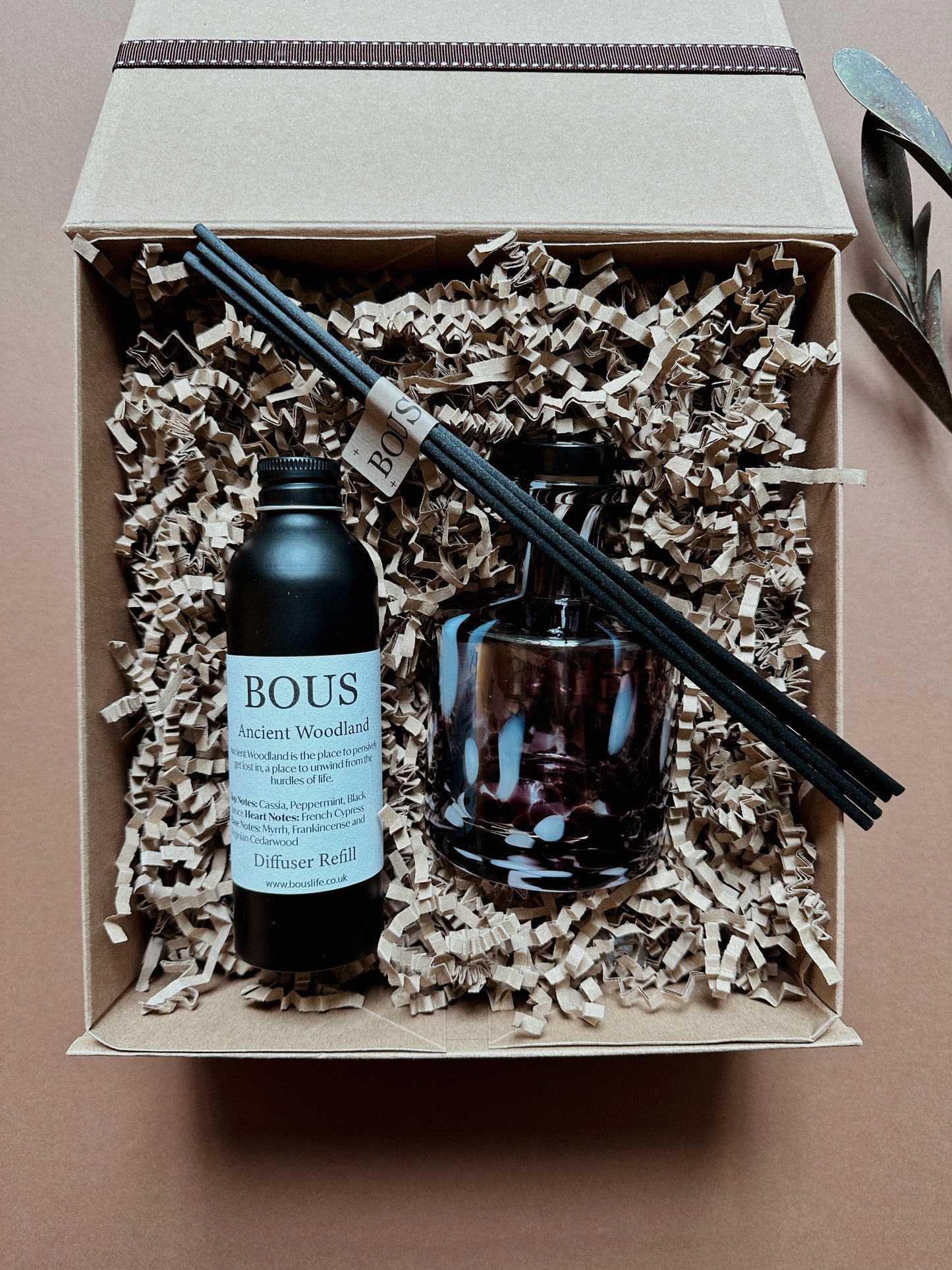 Diffuser set with bottle, candle, and sticks in a box on a brown background