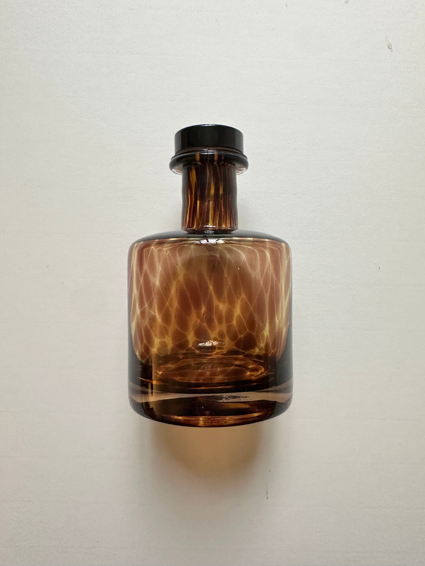 Brown glass bottle with a tortoiseshell patterned design on a white background