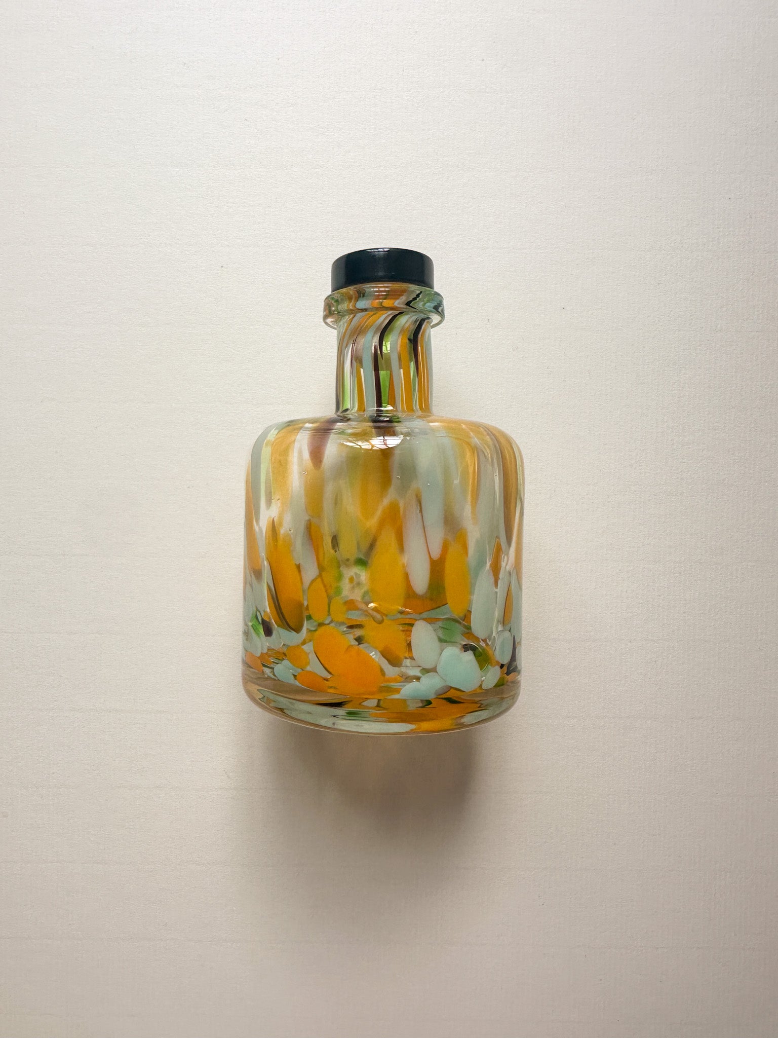 Decorative glass bottle with splodge patterns on a plain background
